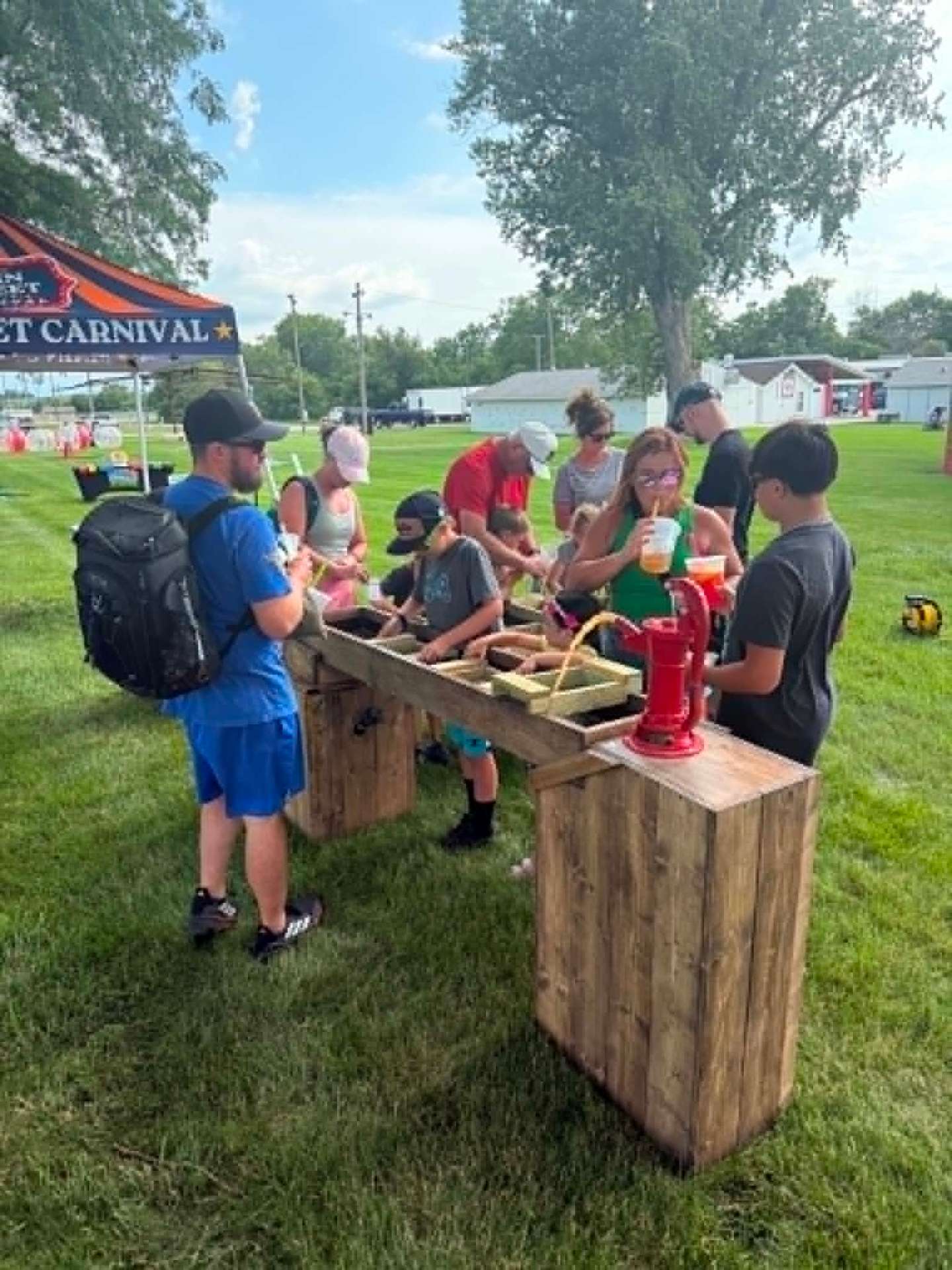 Real-water sluice with red hand pump at a Nebraska festival